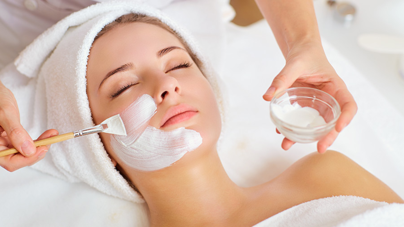 Woman receiving a facial treatment with a brush applying a soothing mask, emphasizing skincare and hydration at Skin & Body Medical Spa.