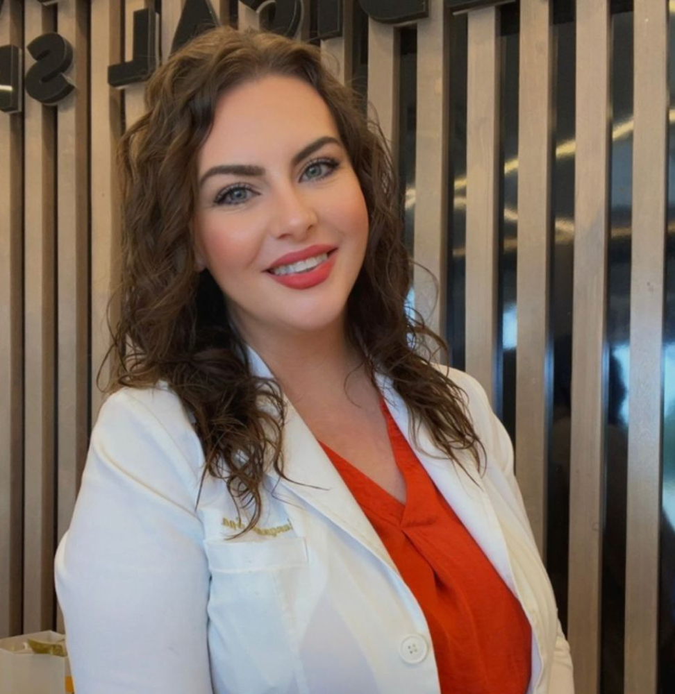 Spa manager and esthetician Meredith smiling in a white lab coat, showcasing expertise in aesthetic treatments at Skin & Body Medical + Wellness Spa.